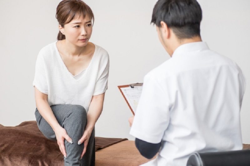 こむら返りで医師の診察を受ける女性