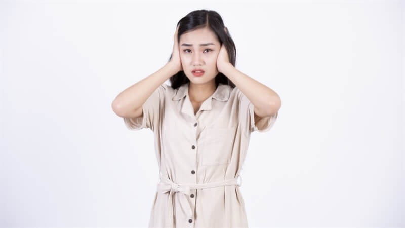 耳をふさぐ女性