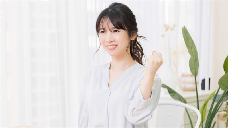 部屋でガッツポーズをする若い女性